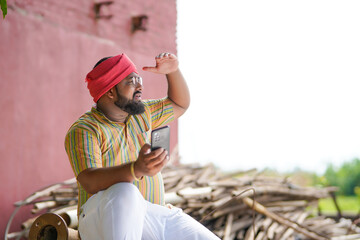 Happy indian farmer using smartphone