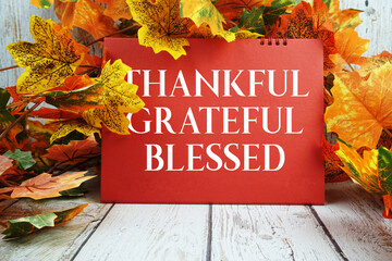 Thankful Grateful Blessed text with maple leaf decorated on wooden background