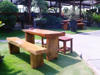 Set up a layout of wooden tables and chairs for an outdoor restaurant or cafe