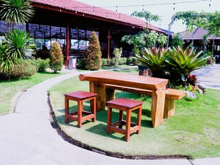 Set up a layout of wooden tables and chairs for an outdoor restaurant or cafe