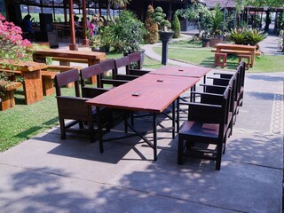 Set up a layout of wooden tables and chairs for an outdoor restaurant or cafe