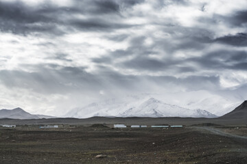 Dramatic landscape panorama of mountain peaks with snow and glaciers in cloudy weather, rays of the sun breaking through the clouds, landscape of the Pamir mountains for the background