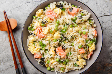 Salmon fried rice with egg, seaweed and vegetables close-up on bowl on the table. Horizontal top view from above