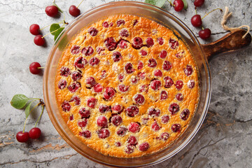 Cherry clafoutis is the taste of summer, fruity and generous close-up in a baking dish on the table. Horizontal top view from above
