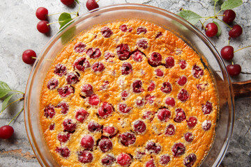 Homemade cherry clafoutis pie with fresh berries and vanilla close-up in a baking dish on the...