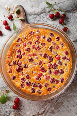 Summer cherry clafoutis pie with fresh berries close-up in baking dish on table. Vertical top view from above