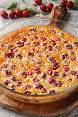 Classic dessert cherry clafoutis pie with fresh berries close-up in baking dish on table. Vertical