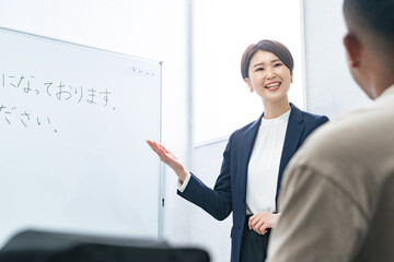 A female teacher teaches business terms to a black man at a Japanese language school. Japanese...