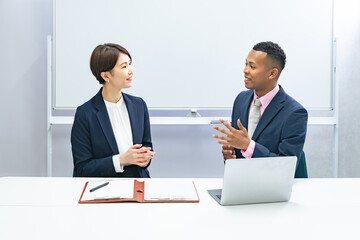 黒人男性ビジネスマンと面談する日本人女性スタッフ