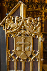close-up of an intricately carved and gilded wooden panel, featuring a prominent heraldic shield