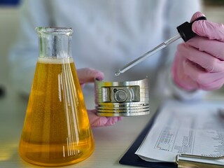 Chemical motor oil on car piston in laboratory closeup. Car piston is examined in laboratory and...