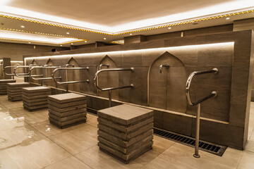 The rows of modern ablution areas, with minimalist cubic benches and steel faucets, curved walls,...