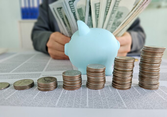 Counting coins and dollar bills near a blue piggy bank during a financial planning session concept