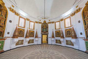 A grand, opulent interior with a central altar surrounded by ornate altarpieces