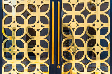Black double doors with gold ornaments in geometric patterns, featuring a combination of circles and flower petals.