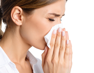 Young woman blowing nose into white tissue suffering from cold, flu, allergies or seasonal illness symptoms