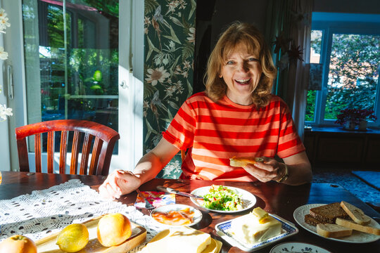Senior woman enjoying a healthy breakfast with salad and bread indoors