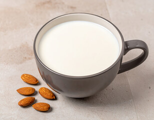 Fresh vegan almond milk pouring into glass surrounded by raw almonds