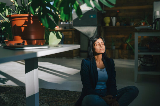 Businesswoman relaxing in a sunny loft office with plants