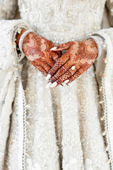 Close-up of bride's hands with henna tattoo and wedding ring. Indian bride wearing elegant wedding...