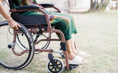 cropped shot, middle age female on wheelchair and hand grip on wheel on grass field at home she resting after being sick