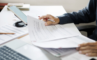 asian businessman working on desk reading and checking financial documents and business contract to make business plan at home office