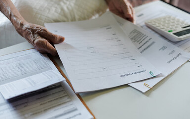 retired adult asian female reading life insurance policy checking bank statement report and savings book before make contract life insurance
