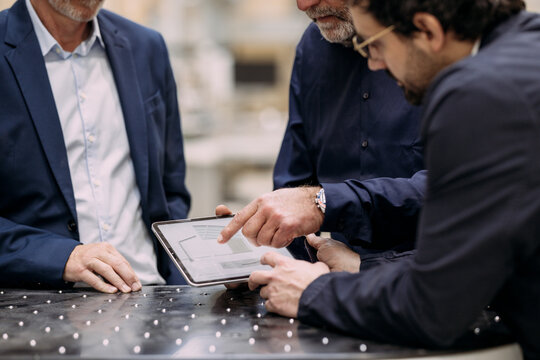 Businessmen discussing strategy using a tablet in an office setting