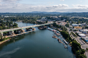 Fototapeta premium Aerial drone picture of Abernethy Bridge and I-205 highway over the Willamette River, connecting Oregon City and West Linn, Oregon, with construction barges, traffic, and scenic surroundings 