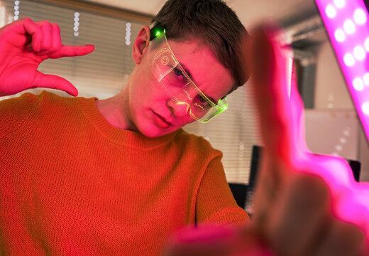 Woman in modern office wearing VR glasses with neon lights