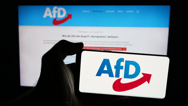 Stuttgart, Germany - 06-26-2025: Person holding mobile phone with logo of German Alternative fur Deutschland (AfD) on screen in front of web page. Focus on phone display.