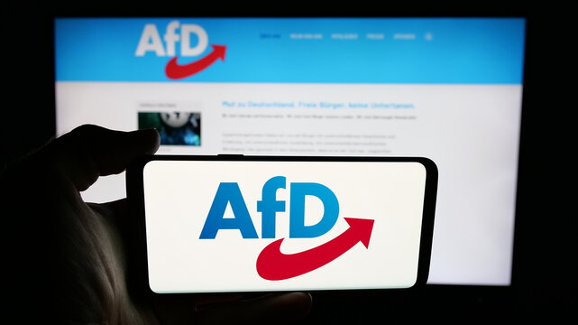 Stuttgart, Germany - 06-26-2025: Person holding cellphone with logo of German Alternative f&uuml;r Deutschland (AfD) on screen in front of webpage. Focus on phone display.