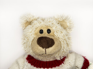 A stuffed teddy bear with a red and white striped sweater on a white background, flay lay, top view. The bear has brown eyes and a brown nose