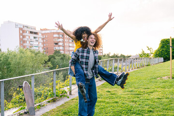 Carefree couple having fun with inline skates in a city park, enjoying a playful piggyback ride during a sunny day