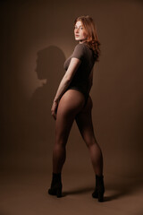 Stylish redhead model with freckles turning sideways in sheer bodysuit