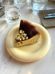 San Sebastian Cheesecake with Pistachios on Table. Modern Desserts Concept. Handheld Phone Photo,...