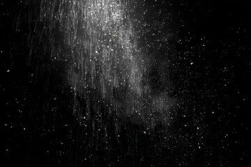Abstract grayscale image of falling particles against a black background