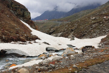 mountain stream flowing through the snow covered alpine valley at marhi near rohtang pass, himalaya...