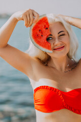 Watermelon Beach Summer Woman: Happy blonde playfully holds watermelon slice, summer beach photo.