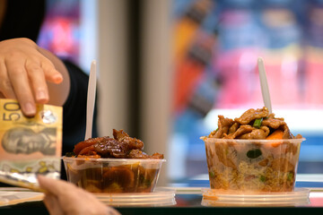Take away stir fry food being served into a container by hand