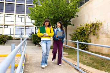 Two smiling university students walking and talking on campus