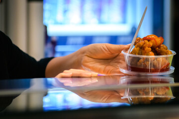 Take away stir fry food being served into a container by hand