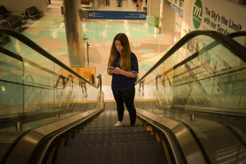 Side view female teenager on mobile phone in airport