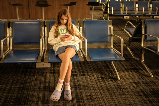 Front view tween girl texting on cell phone airport gate