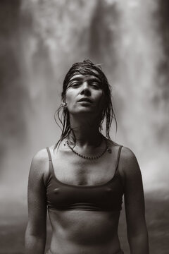 Wet woman standing before powerful Nungnung waterfall