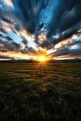The sun glowing through a break in the clouds over a peaceful meadow