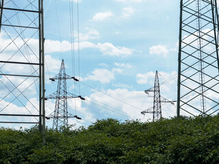 High voltage power lines crossing over greenery on a clear day