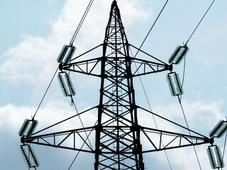 High voltage transmission tower against cloudy sky background
