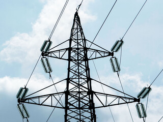 High voltage transmission tower against cloudy sky