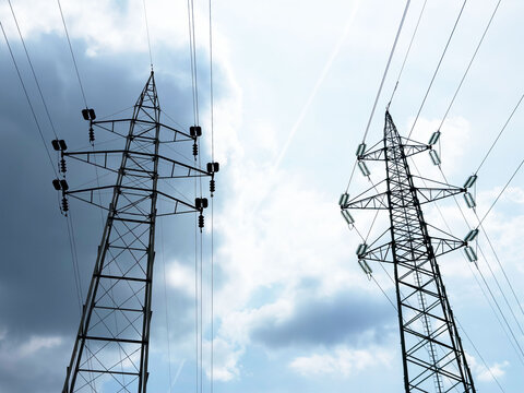 High voltage power lines against blue cloudy sky